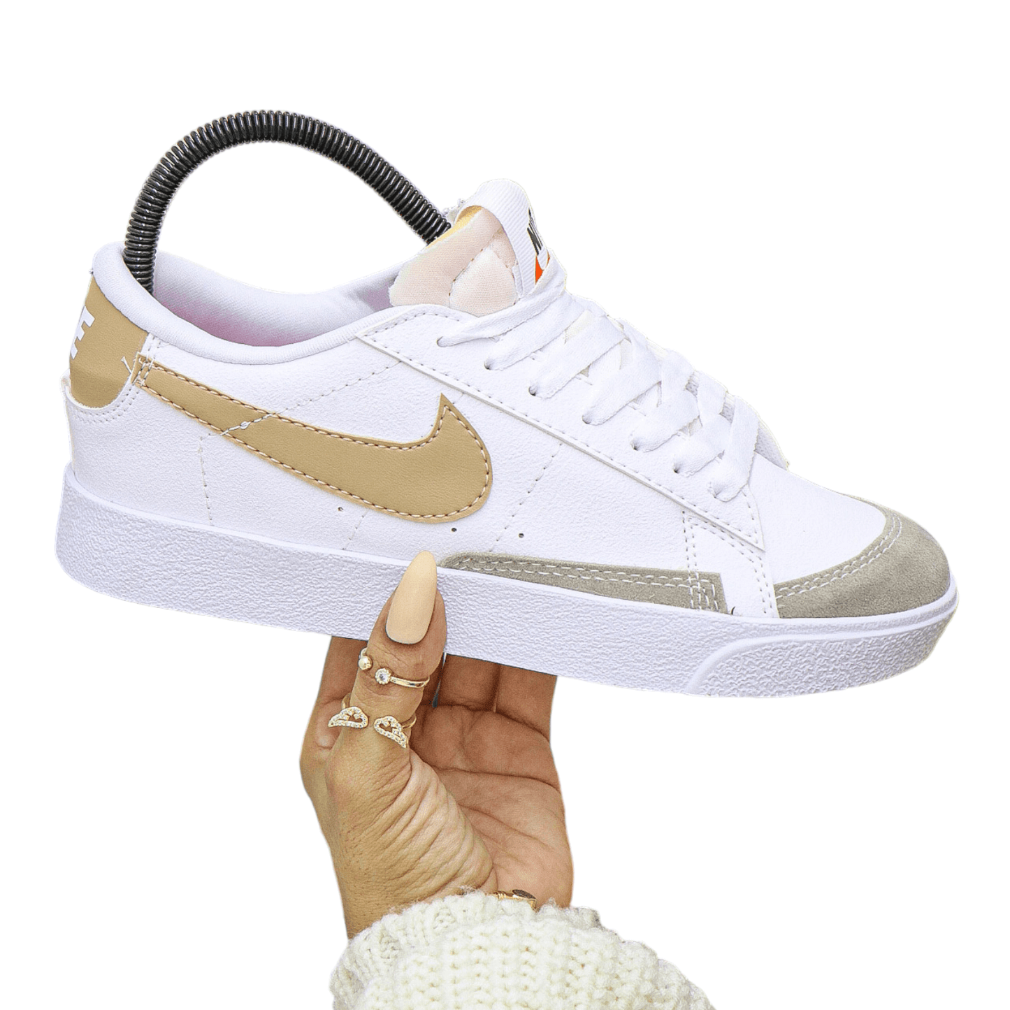 Mujer sostiene un tenis Nike Blazer blanco con detalles en cuero y gamuza beige. Diseño retro y cómodo para estilo urbano.